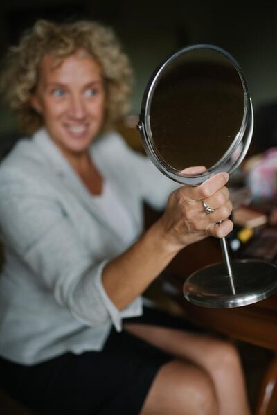 File:Woman looking at her reflection in the mirror and smiling (51528984894).jpg