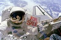 Astronaut Dale Gardner holding a "For Sale" sign