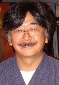 A 46-year-old Japanese man smiling directly into the camera. He has black hair going to gray around the temples and a graying mustache.