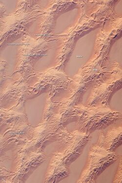 Marzuq Sand Sea seen from ISS, 2008 (centered at [ ⚑ ] 24°30′N 12°00′E﻿ / ﻿24.5°N 12°E﻿ / 24.5; 12). Detailed astronaut photograph, taken from low earth orbit, showing classic large and small sand masses of the central Sahara where wind is a more powerful land-shaping agent than water.