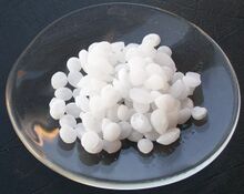 Sample of sodium hydroxide as pellets in a watchglass