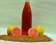 A bottle of guava seed oil surrounded by fruit