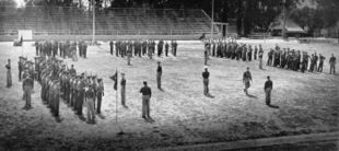 Soldiers standing in formation in groups on an American football field