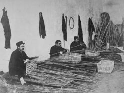 Black and white photo of three men weaving wicker baskets