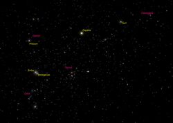 Simulated night-sky image centred on Orion labelled with constellation names in red and star names in yellow, including Sirius very close to Betelgeuse and the Sun near Cassiopeia.