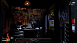 A gameplay screenshot showing the inside of the protagonist's office. Posters and memorabilia of the animatronics are plastered on the walls. A set of computer monitors and a fan sit atop the office's desk. To the right of the room is an open hallway, with an animatronic designed like an anthropomorphic yellow chicken peering inside the office.
