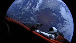 Large circular disc of a fully illuminated planet Earth floating in the blackness of space. In front of Earth is a red convertible sports-car seen from the side. A humanoid figure wearing a white-and-black spacesuit is seated in the driving seat with the right-arm holding the steering wheel, and the left-arm resting on the top of the car door.