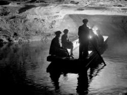 Several people in a jon boat on a river inside a cave.