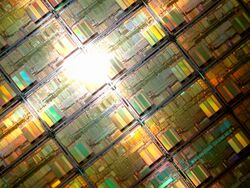Silicon wafter covered in a tiled pattern of transistors for processors reflecting sunlight in rainbow patterns