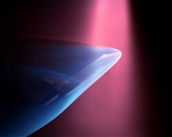 A violet beam from above produces a blue glow about a Space shuttle model