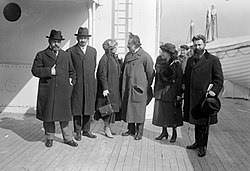 Casual group shot of four men and two women standing on a brick pavement.