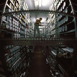 A man on a walkway between two high shelf racks loaded with ice core samples