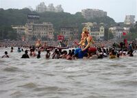 Large Murti of Ganesh on the water, surrounded by people