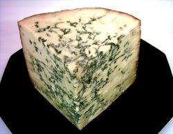 A corner of cheese with greenish streaks through it