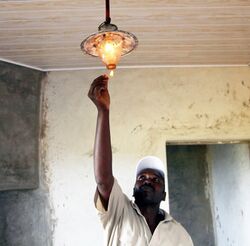 Man lighting a lamp hung from the ceiling