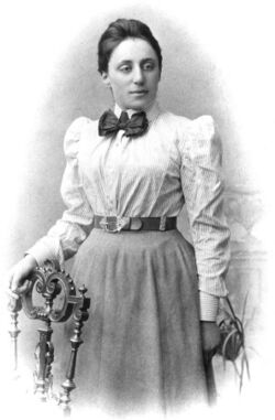 A portrait of Emmy Noether looking slightly to the side with her hand resting on a chair