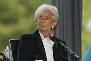 A three-quarter portrait of an elegantly dressed Christine Lagarde, perhaps in her early 60s sitting in a chair behind a microphone. She looks fit and tanned. Her overall mien is alert, pleasant, and intelligent.